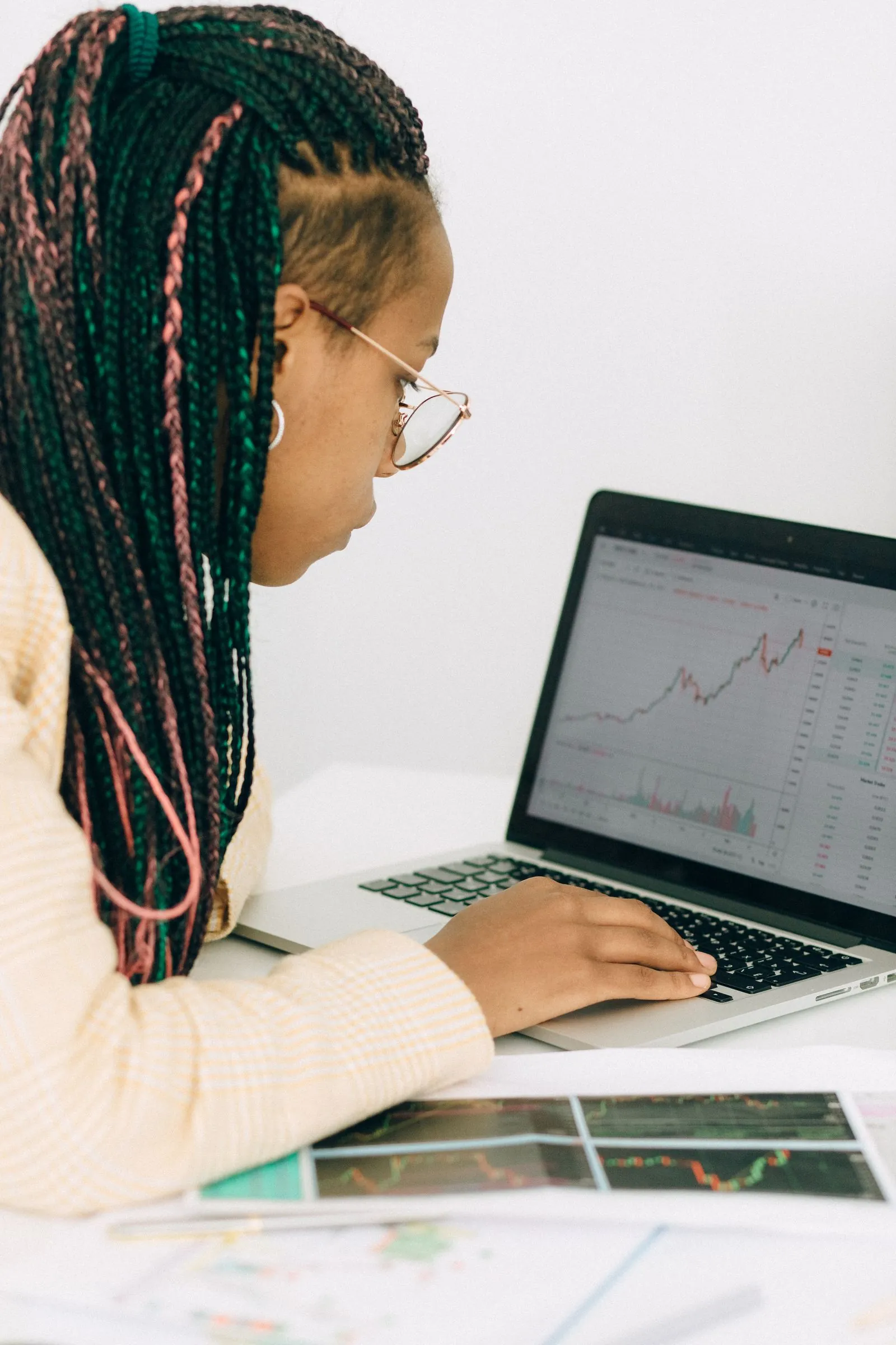 A woman studies market charts on her laptop.