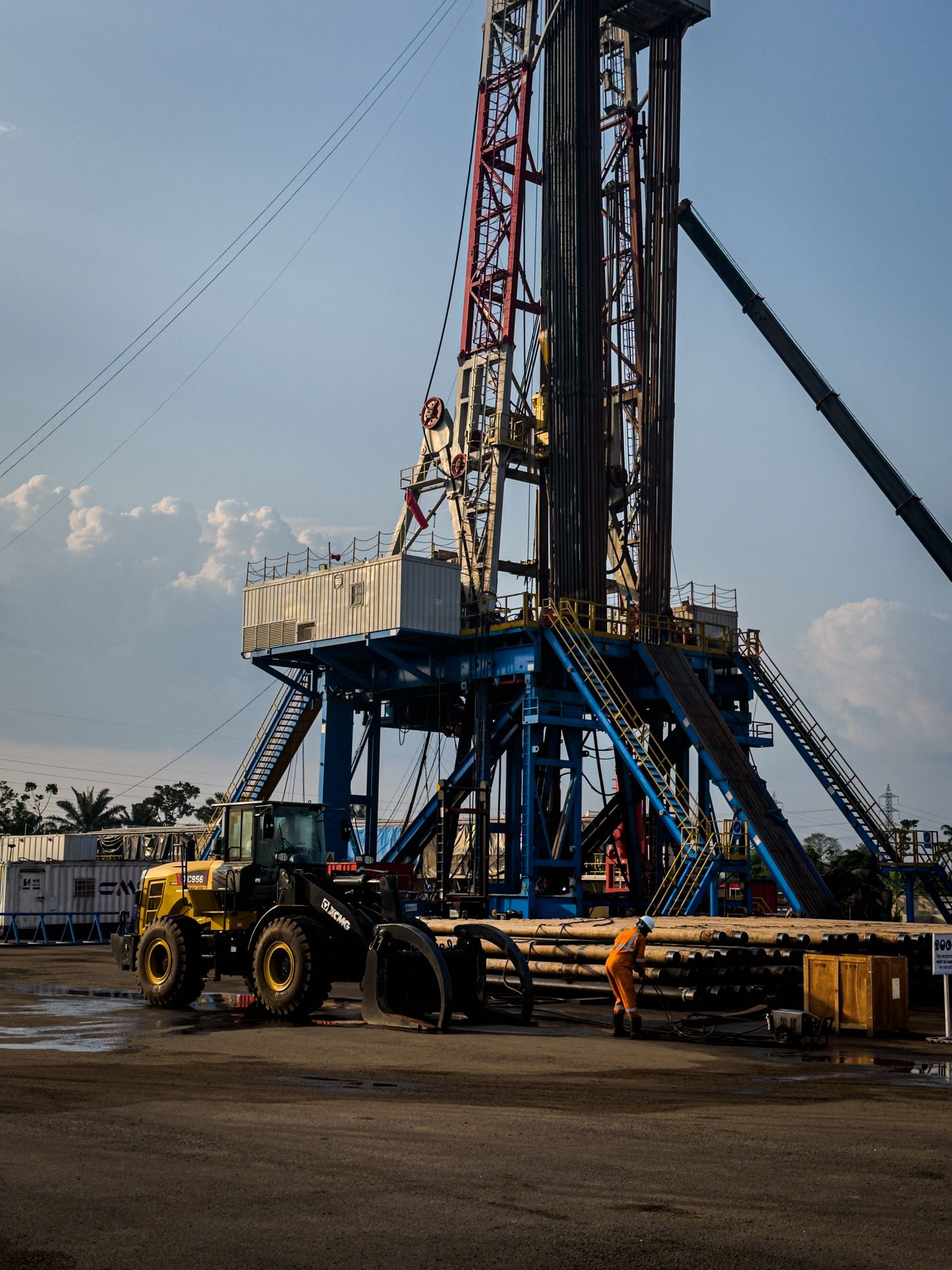 An oil-field worker stands beside drilling equipment at a rig.