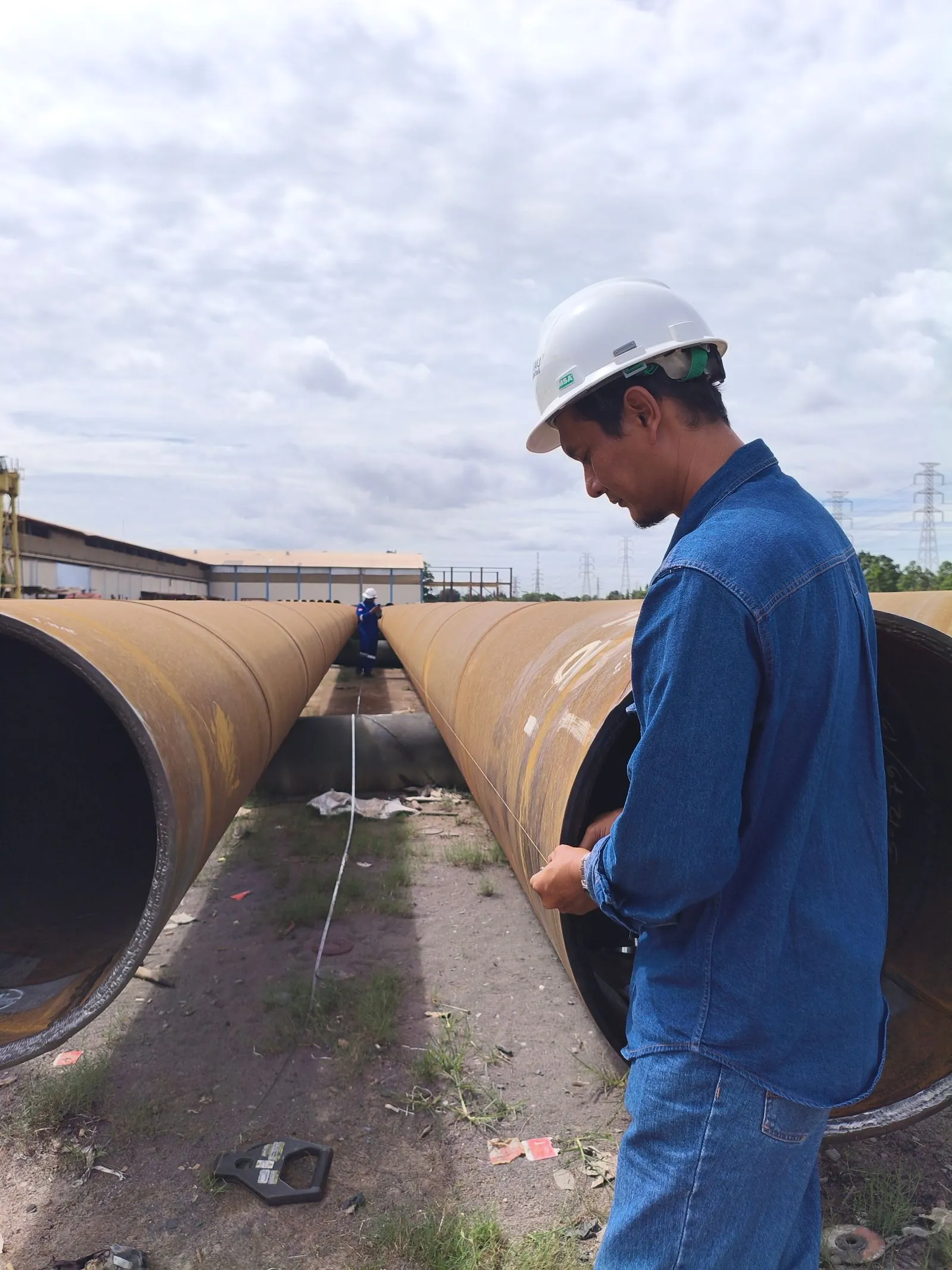 An engineer inspects large energy pipelines under construction.