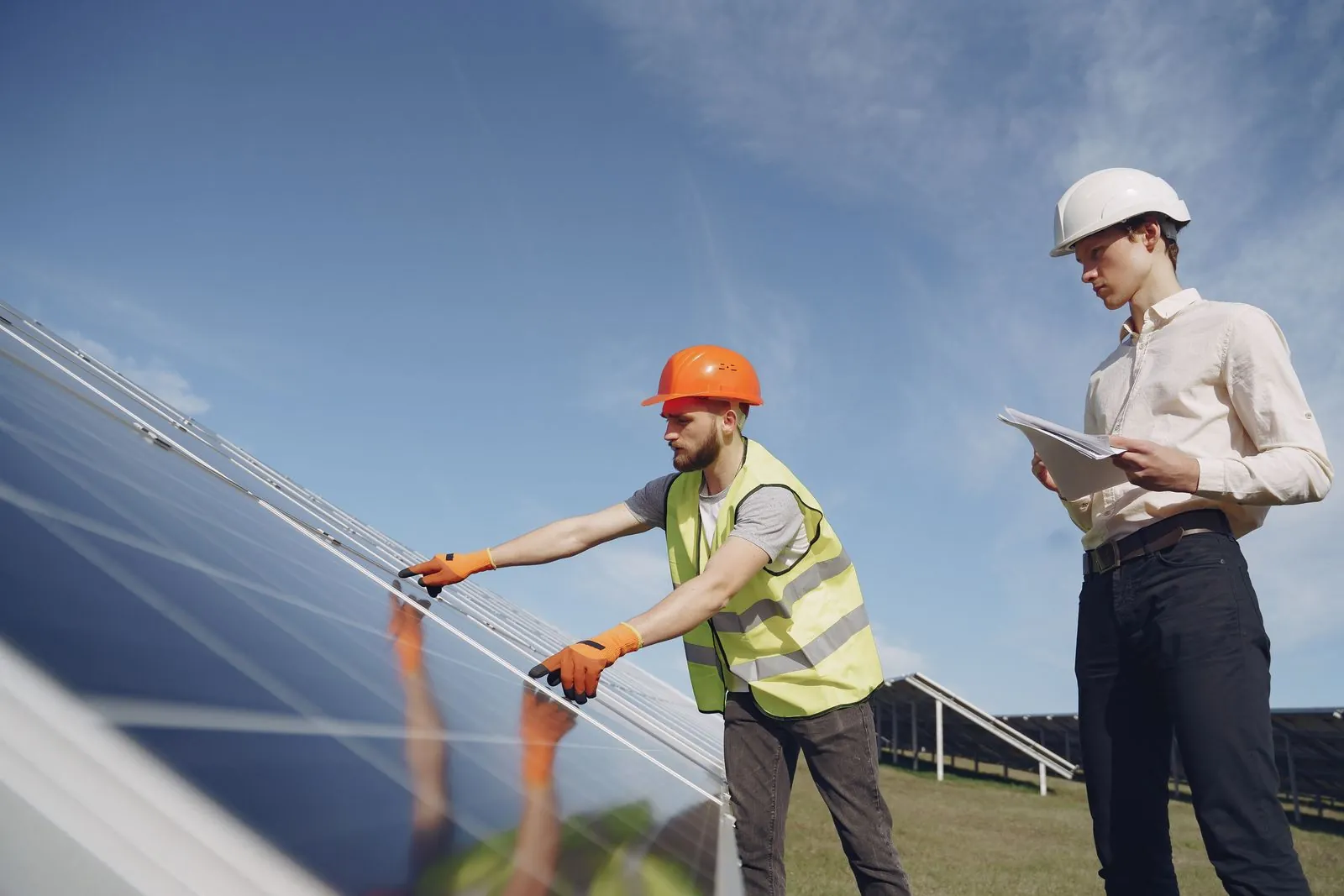 Two solar technicians inspect photovoltaic panels.