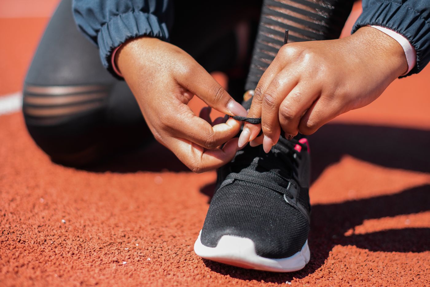 An athlete ties running shoes on an outdoor track.