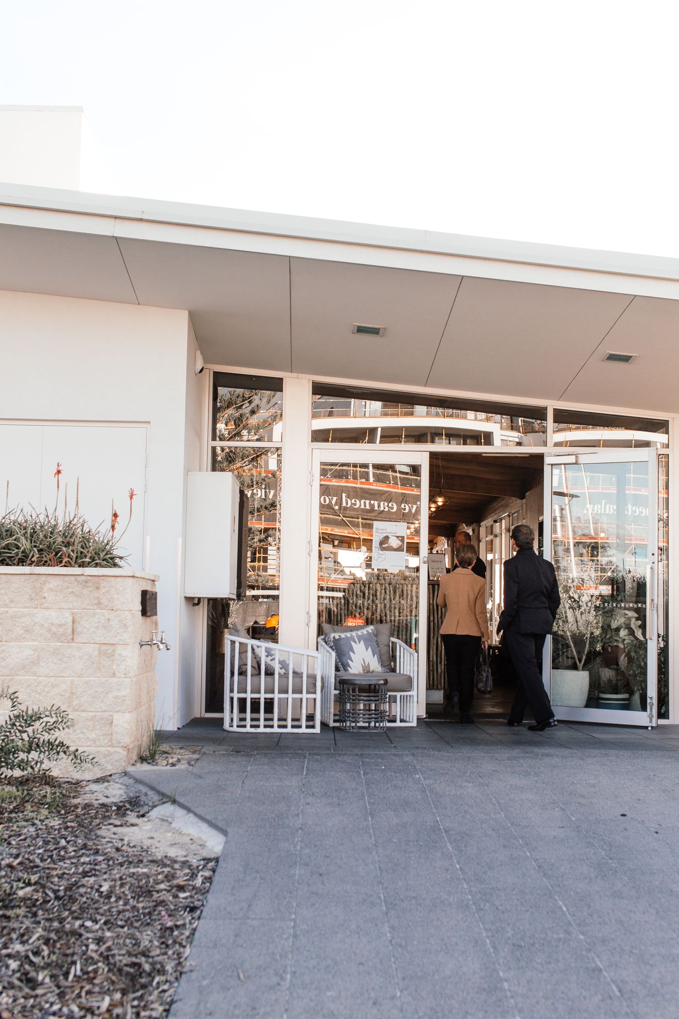 Two customers enter a glass-fronted retail store.
