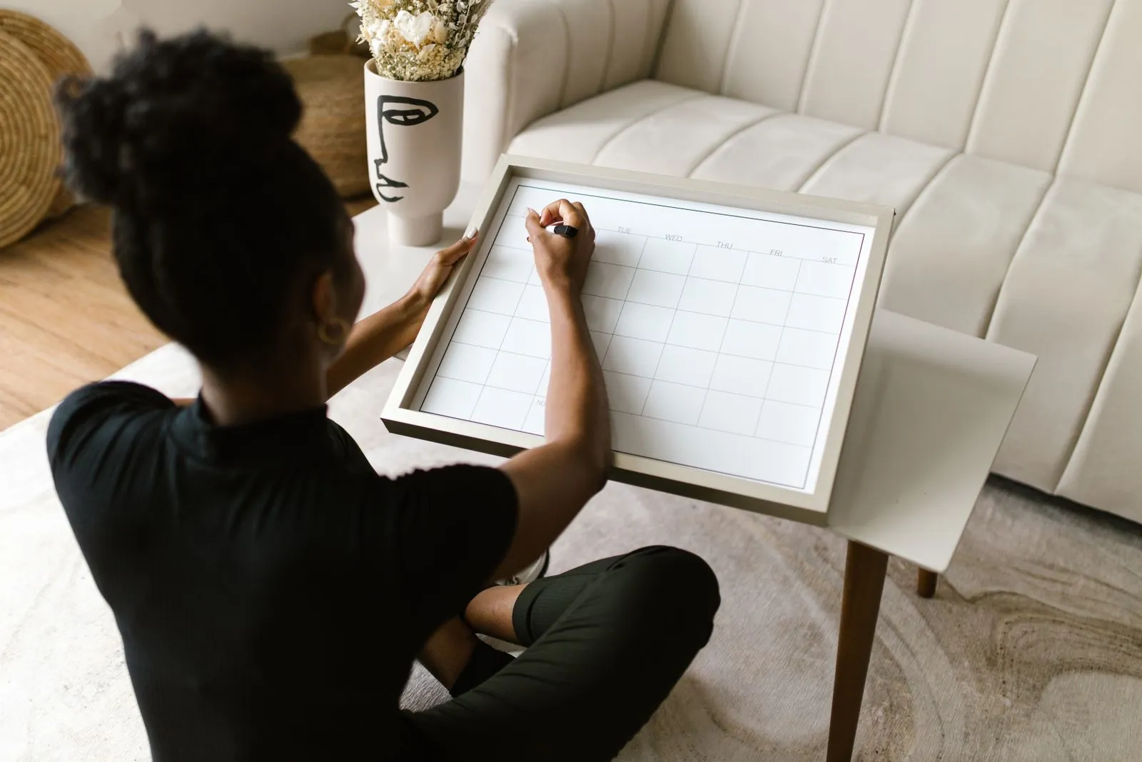 A woman plans dates on a paper calendar at home.